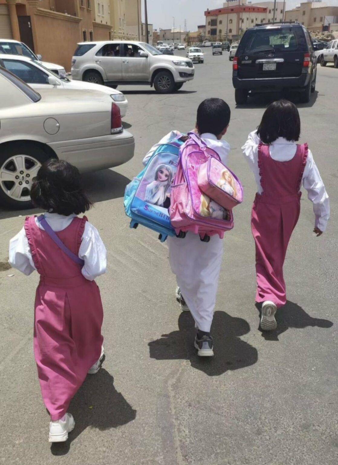 تفاعل واسع لصورة طفل يحمل حقائب أختيه أثناء ذهابهم للمدرسة